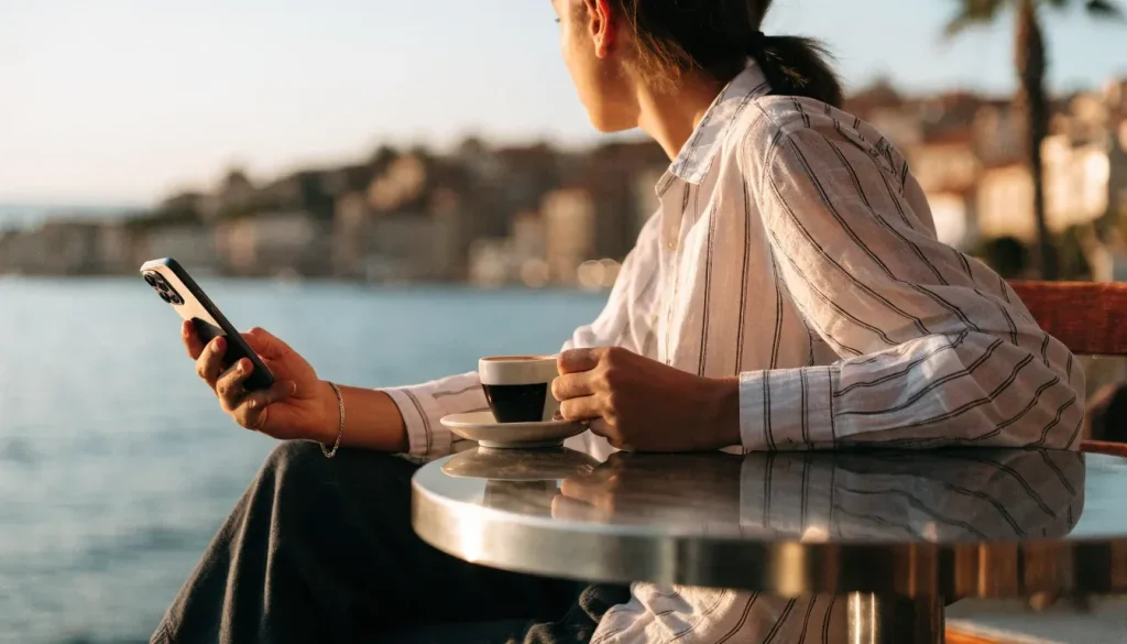 Osoba drži smartphone na terasi kafića uz jadransku obalu